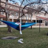 Student sitting in a hammock on campus