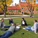 People sit in a circle on a campus lawn. 