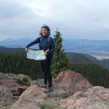 Sabrina Kainz holds up a map while standing on a rocky overlook