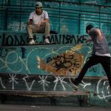 Boys skateboarding by a graffiti wall