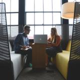 Students sit across table looking at laptop