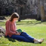 student reading a book on campus
