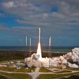 The Atlas V rocket takes off from a launch pad.