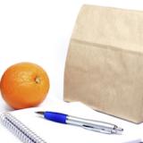 A brown paper bag, pen, and orange