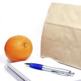 A brown bag, notepad, pen and orange
