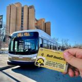 Person holding a Buff OneCard with a Buff Bus in the background