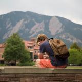 Student sitting alone on brick wall on campus