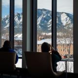 People sit in lounge chairs inside a campus building.