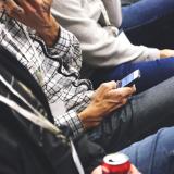 Students sit and look at their mobile phones