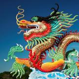 A colorful Chinese dragon sculpture with a bright blue sky in the background.