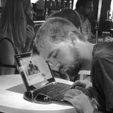 A student listens to his laptop in a noisy coffeeshop setting