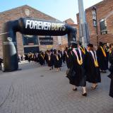 Graduates walk through Forever Buffs arch