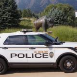 A CUPD car in front of a bronze buffalo statue on campus.