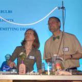 Two faculty members present a electrical light-based experiment.