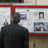 Person reading newspaper clips in a display box