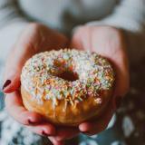 Person holding donut with sprinkles