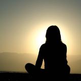 silhouette of person meditating at sunset