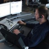 Dispatcher sits at desk with five computer monitors