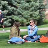 Two students chat sitting on lawn