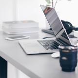 Unattended desk with laptop, camera lenses, mobile phone, headphones