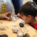 Child examines artifacts under magnifying glass