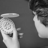 black and white photo of woman holding birth control pills