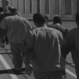 A black and white illustration showing black men in prison uniforms