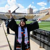 Valeria Ayala Alonso celebrates after getting her photo taken at Folsom Field during Grad Appreciation Days events