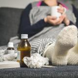 Sick person on couch with cold care supplies
