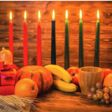 A Kwanzaa centerpiece with candles and fruit.