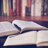 Open book and notepad on library table