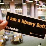 Person holding a 'I am a library Buff' bumper sticker