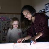 Researchers play with child over lighted table