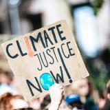 Person at a protest holding up a 'climate justice now' sign