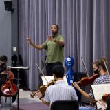  Kedrick Armstrong, a music+ scholarship recipient, conducts a group of musicians on strings.