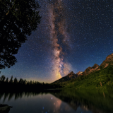 Milky Way over a lake, trees and mountains