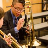 Middle School Ensemble participants with trombones reviewing music