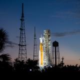 Rocket on a launch pad with trees and antennas in foreground