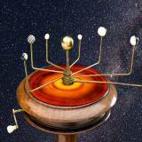 An orrery, a type of device once used to track the movements of the planets, sitting above an infrared image of a hypothetical "protoplanetary" disk that may have divided the solar system early in its history.