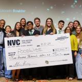 Students posing in front of large one hundred thousand dollar check.