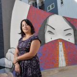 Noreen Naseem Rodriguez stands in front of a mural