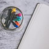 Highlighters in a jar next to notebook