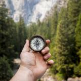person holding compass in the mountains