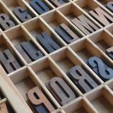 Letterpress letters are resting in a wooden box.