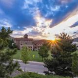 Sun peaks over a building on campus