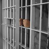 a man holding the bars of a prison cell