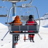 mountain skiers riding on chair lift