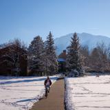 Student riding a bike on a snowy campus