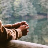 Person holds hands together, looking outside