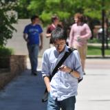 Student walking on campus, looking at smartphone